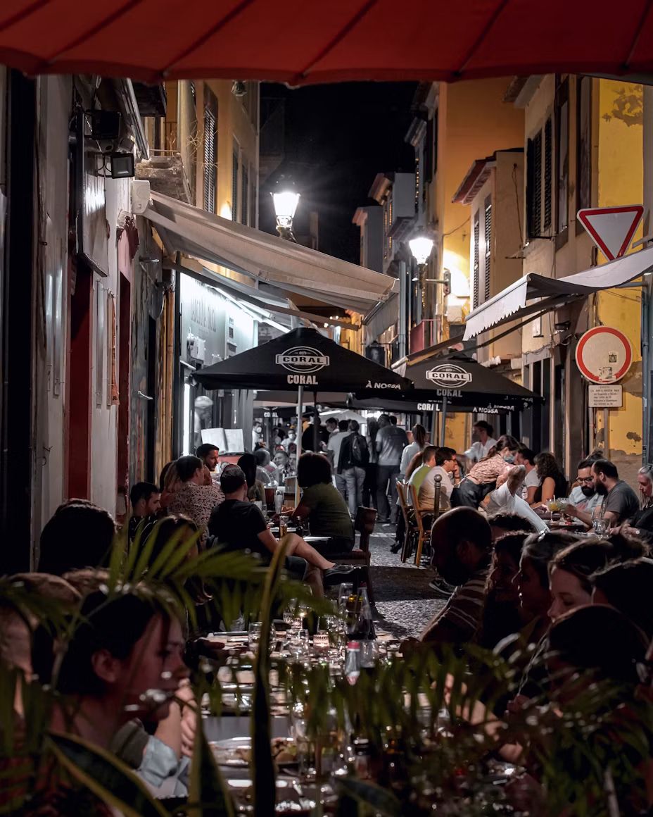 Gasse in der Altstadt von Funchal mit besetzten Restauranttischen am Abend